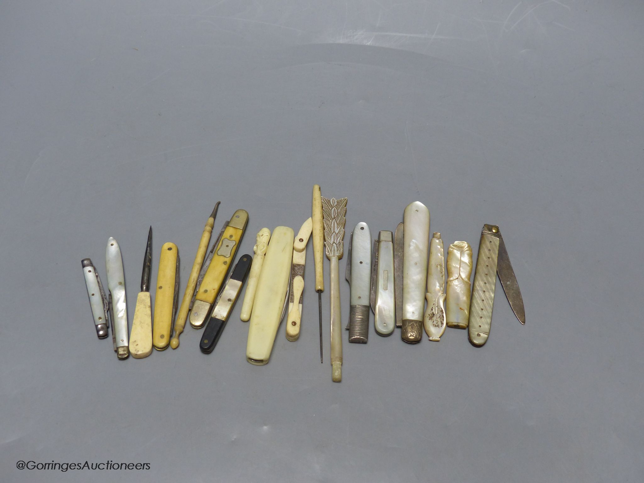 A group of silver and steel bladed pocket folding knives and a fork
